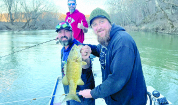 Guide Tommy Bench holds Nathan "Shags" McLeod's Gasconade River dinosaur, with Adam Voight admiring the catch.